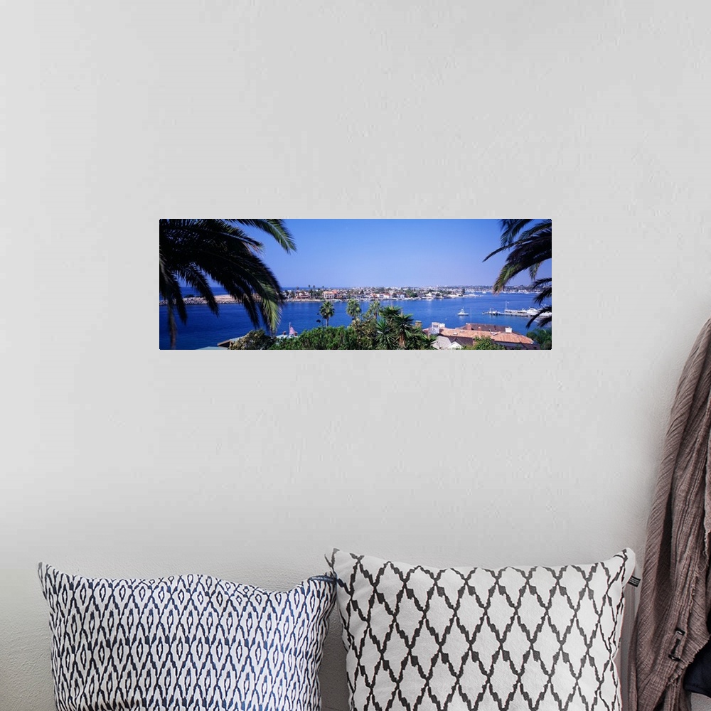 A bohemian room featuring Panoramic photograph of small town on an island seen from behind huge palm leaves.