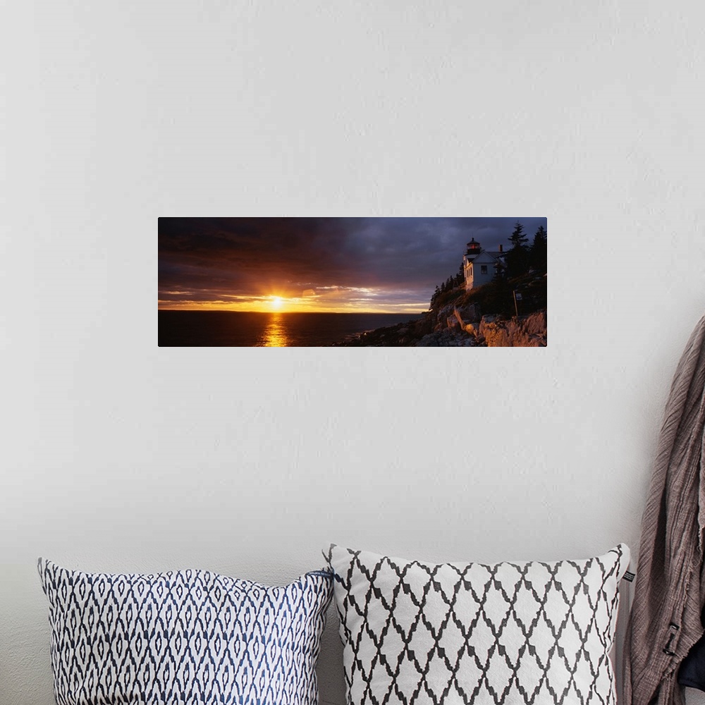 A bohemian room featuring Large panoramic shot of a sun setting over a harbor with a house on a cliff just to the right.