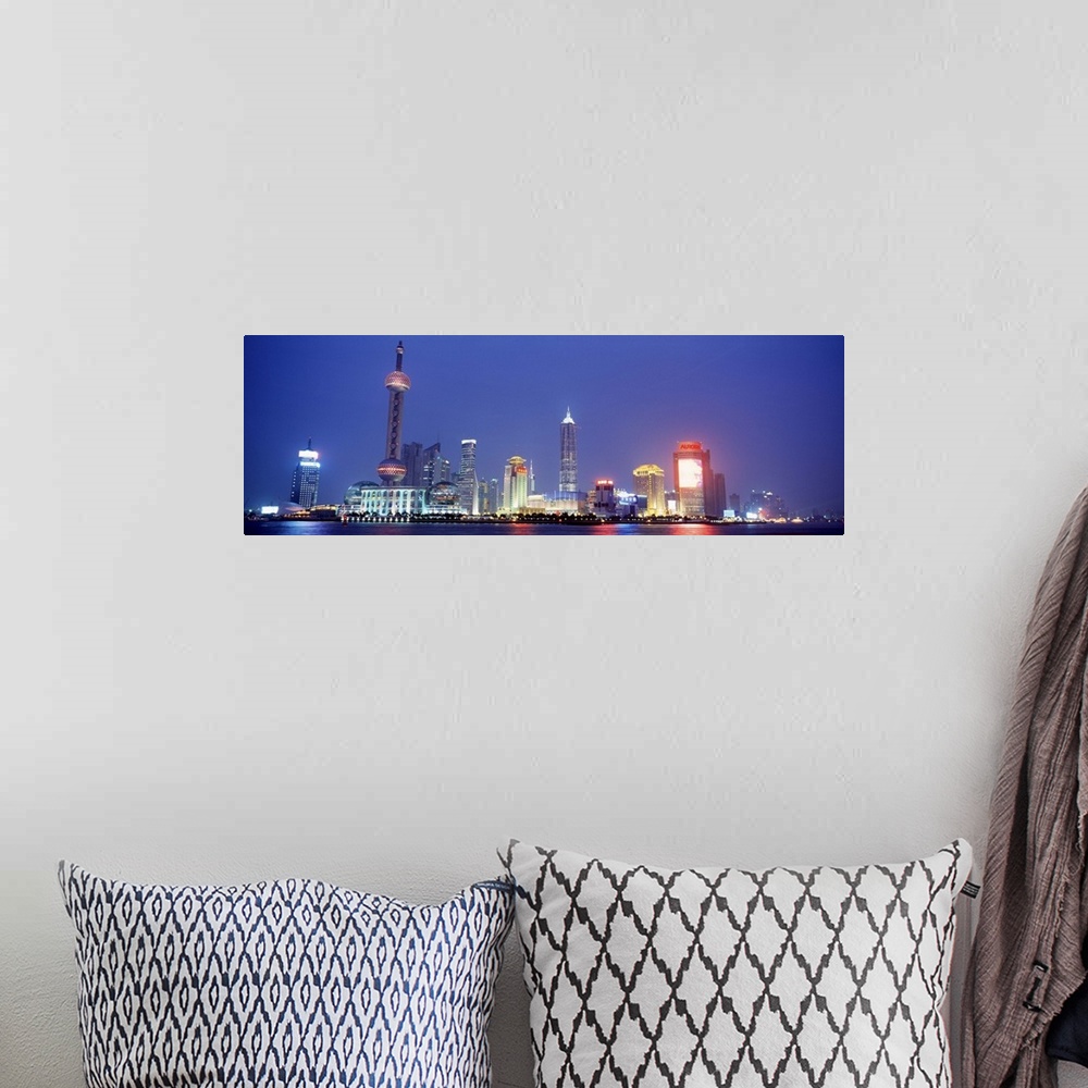A bohemian room featuring Panoramic photograph of skyline and water front at night.