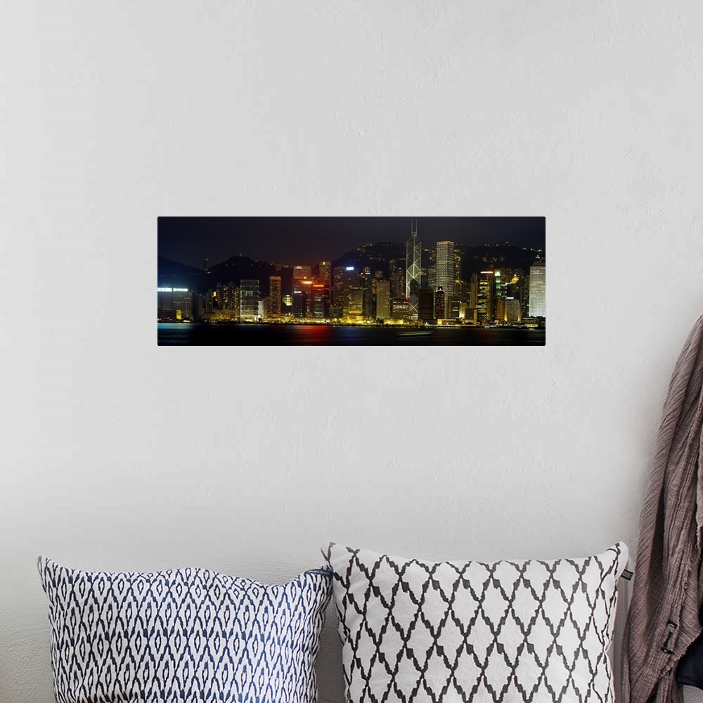 A bohemian room featuring Panoramic photograph of the Hong Kong skyline, lit up at night, reflecting in the water, in China.
