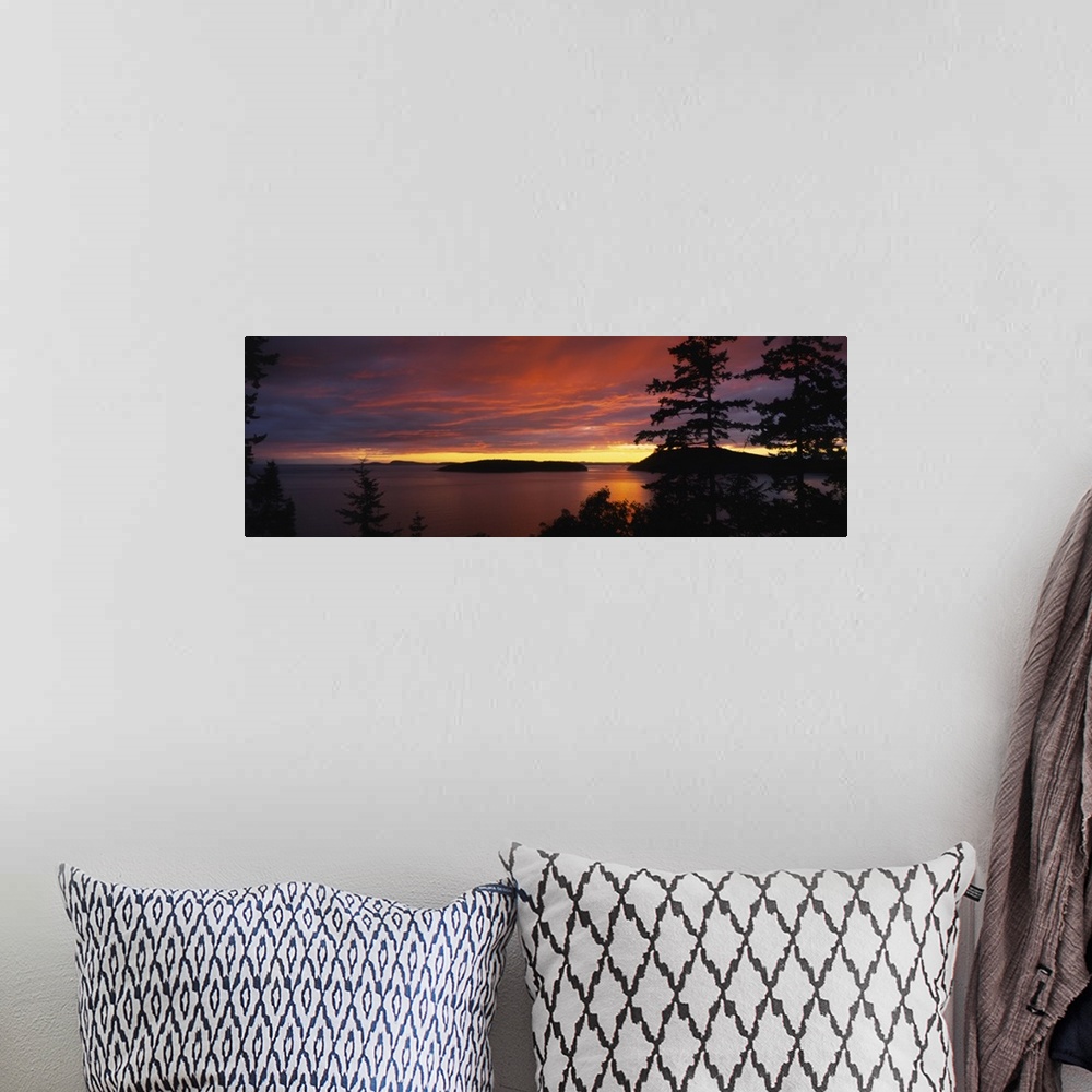 A bohemian room featuring Large, landscape photograph of vibrant clouds in the sky as the sun sets over the Rosario Strait,...