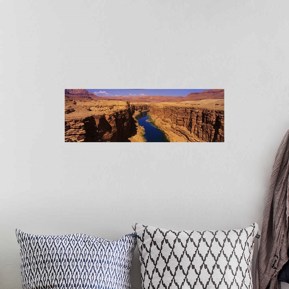 A bohemian room featuring A panoramic photograph of an ancient waterway passing through the rock cliffs it has eroded over ...