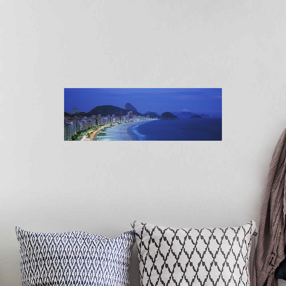 A bohemian room featuring A large panoramic shot of the coast and skyline of Rio De Janeiro. Taken at dusk, the buildings a...