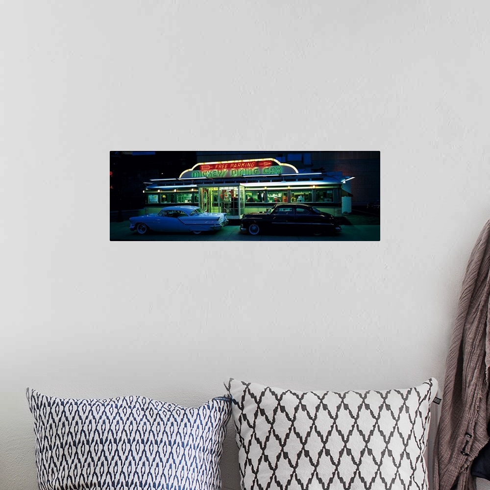 A bohemian room featuring Panoramic photograph of two vintage cars sitting outside of a lit up eatery at night with neon si...