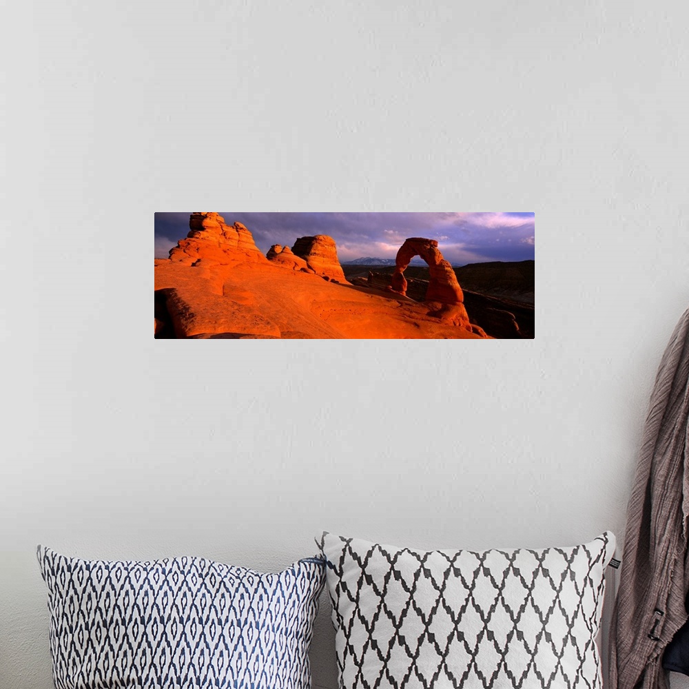 A bohemian room featuring A landscape photograph that is a panoramic shot of a wind eroded rock face illuminated a sunset.