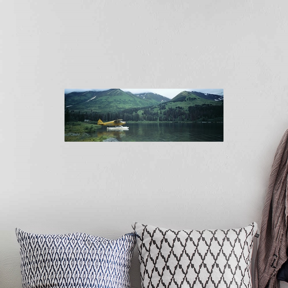 A bohemian room featuring Panoramic photograph of airplane on skis in lake with mountains in the distance.