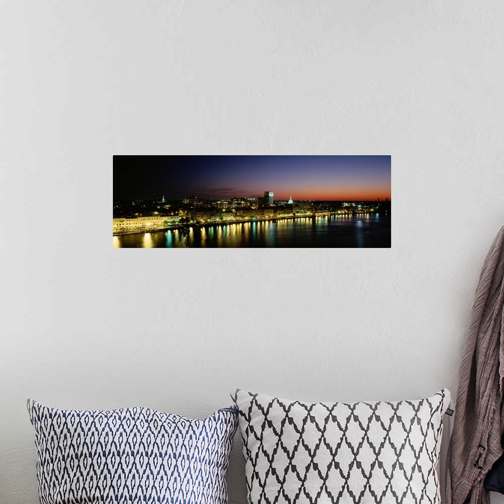 A bohemian room featuring Panoramic photograph of lit up skyline and waterfront at sunset under a colorful sky.