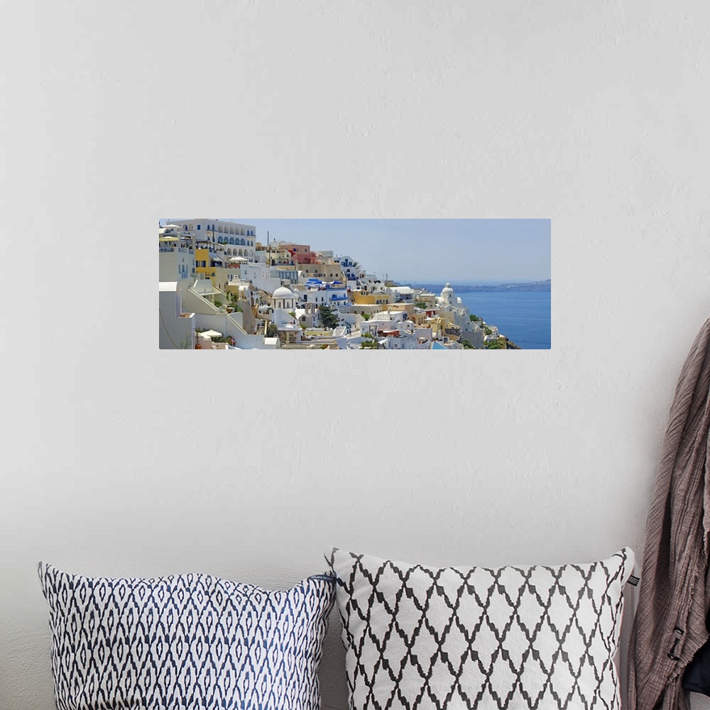 A bohemian room featuring Houses in Greece are photographed from the side as they sit high up in a large cliff off the coast.