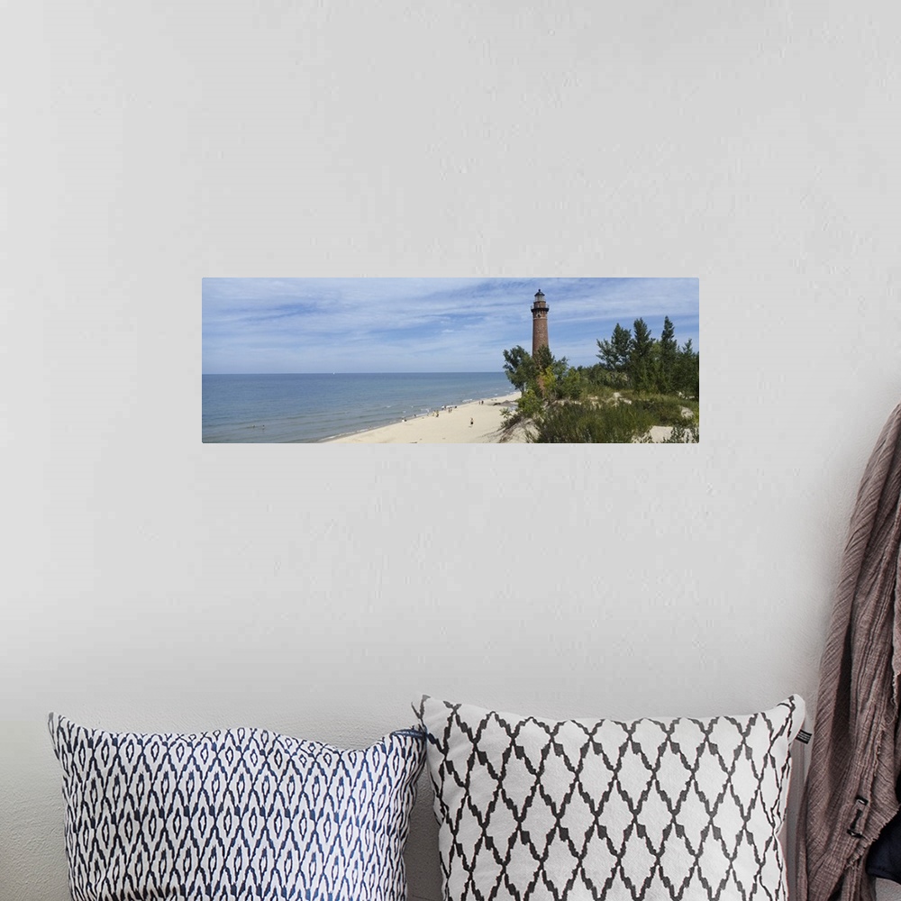 A bohemian room featuring A light house on a sandy shore obscured by costal plant life and a partially cloudy sky.