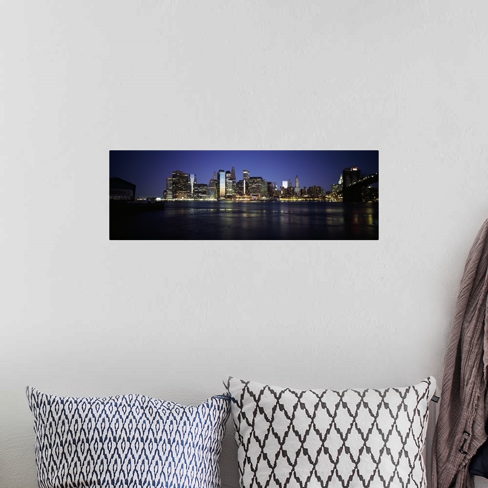 A bohemian room featuring Panoramic photo of the NYC cityscape lit up at night seen from the water.