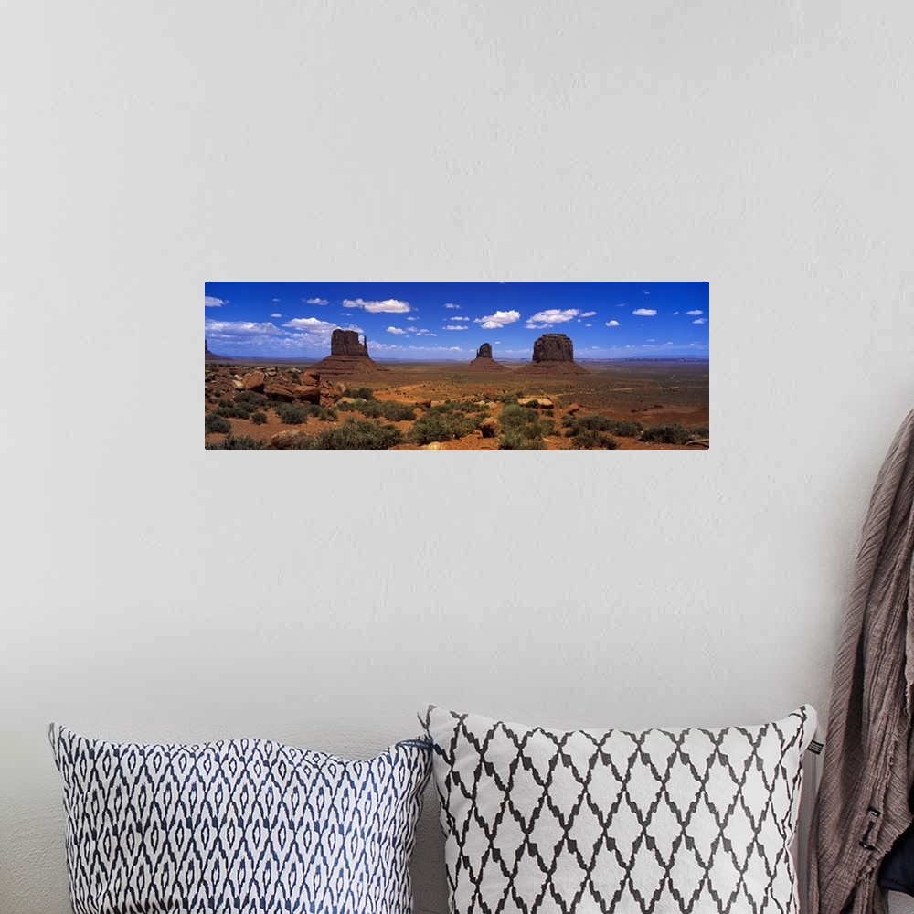 A bohemian room featuring Panoramic photo on canvas of three tall rock formations in the desert under a bright blue sky.