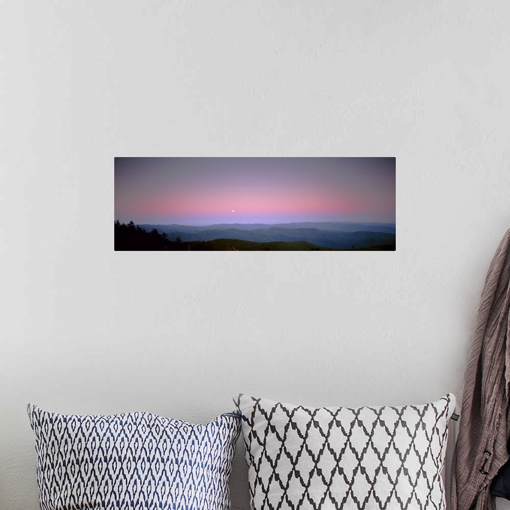 A bohemian room featuring Mountains in the distance are photographed under a sunset sky with a small view of the moon.