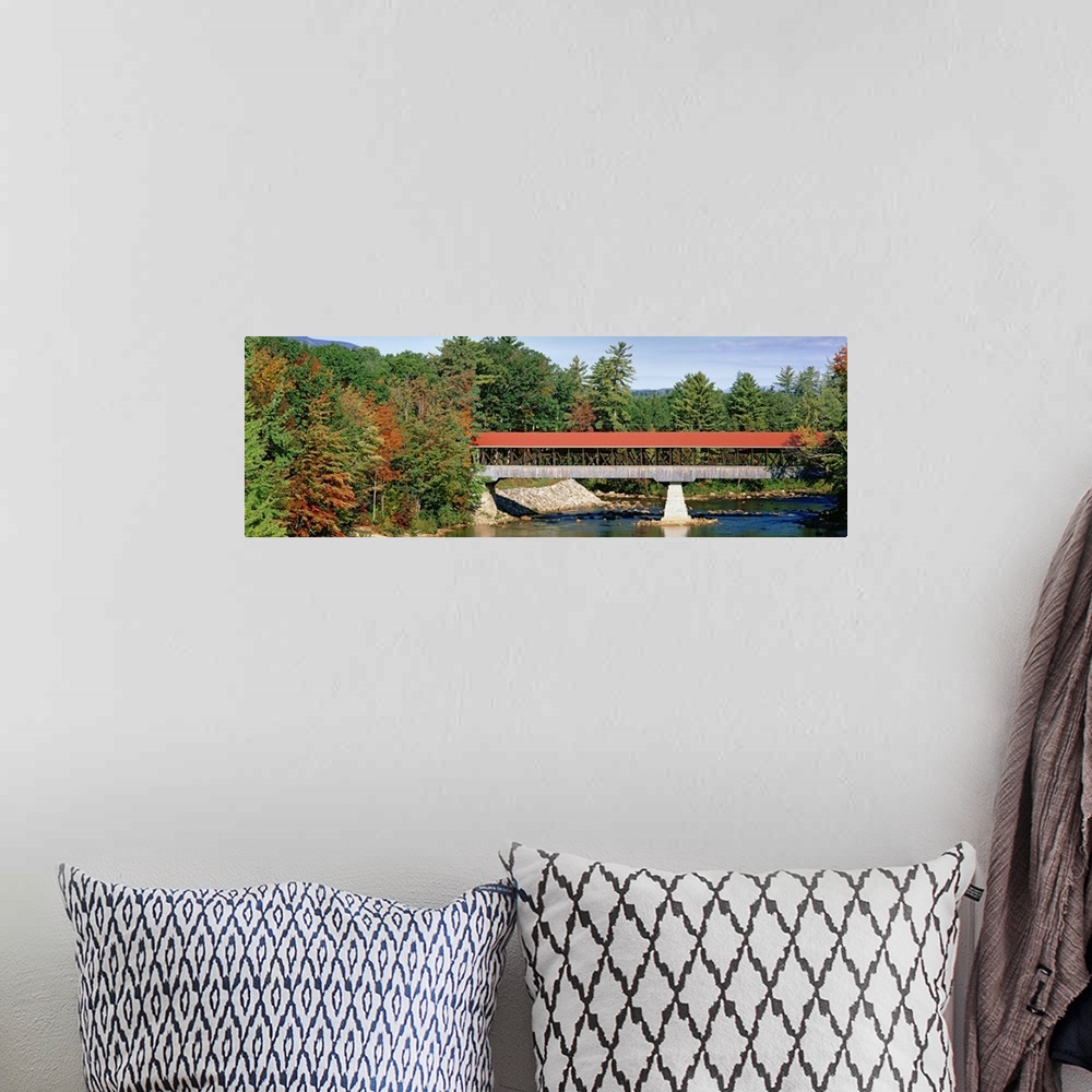 A bohemian room featuring Panoramic image of a red roofed covered bridge spanning a calm tree lined river.