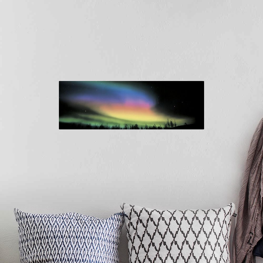 A bohemian room featuring Panoramic photograph taken of the northern lights. Swirls of color brighten the dark night sky.