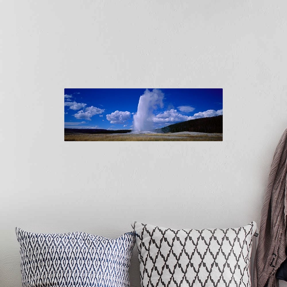 A bohemian room featuring Panoramic photo of a geyser shooting out steam at Yellowstone.