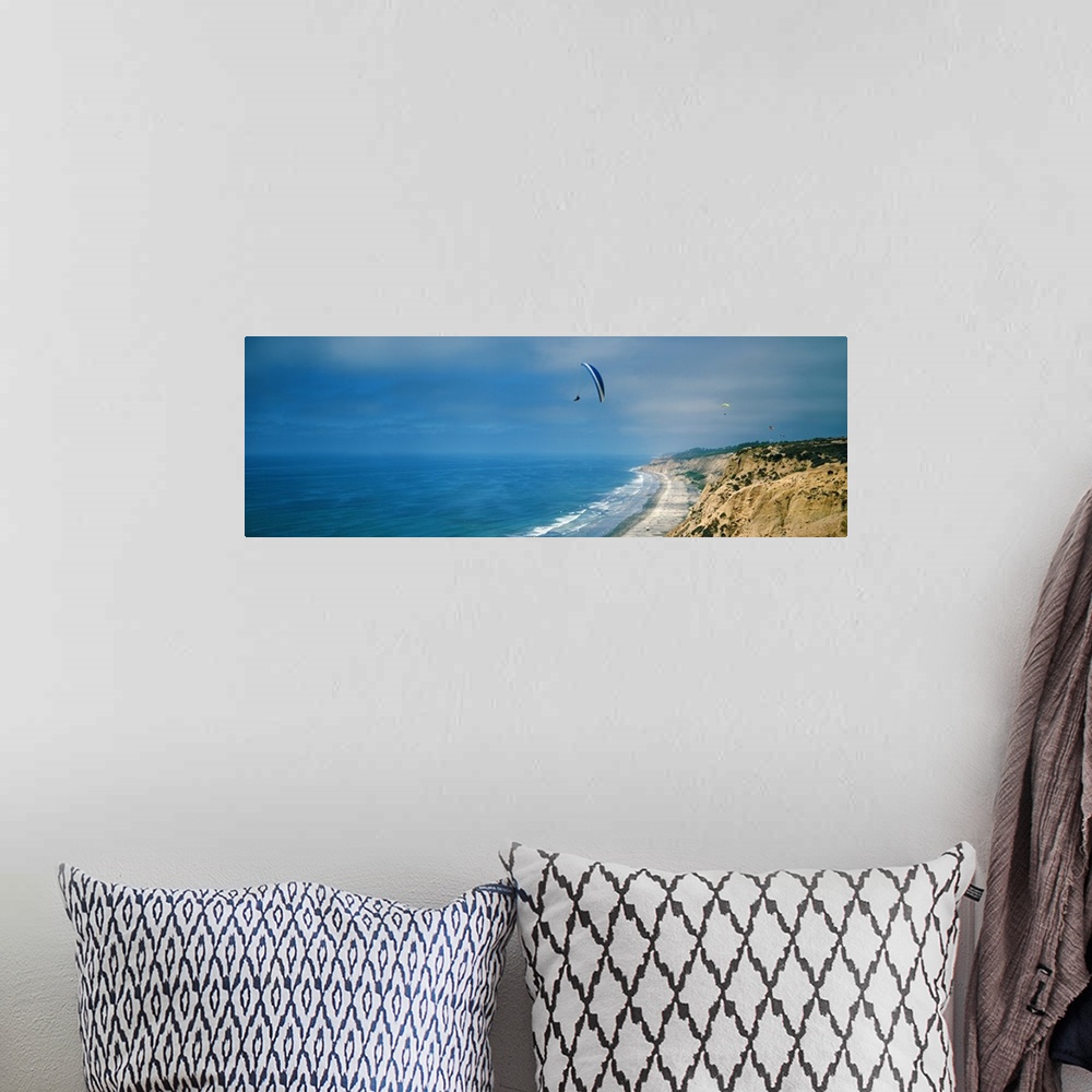 A bohemian room featuring Horizontal photograph on a giant canvas of several paragliders floating over bright blue waters a...