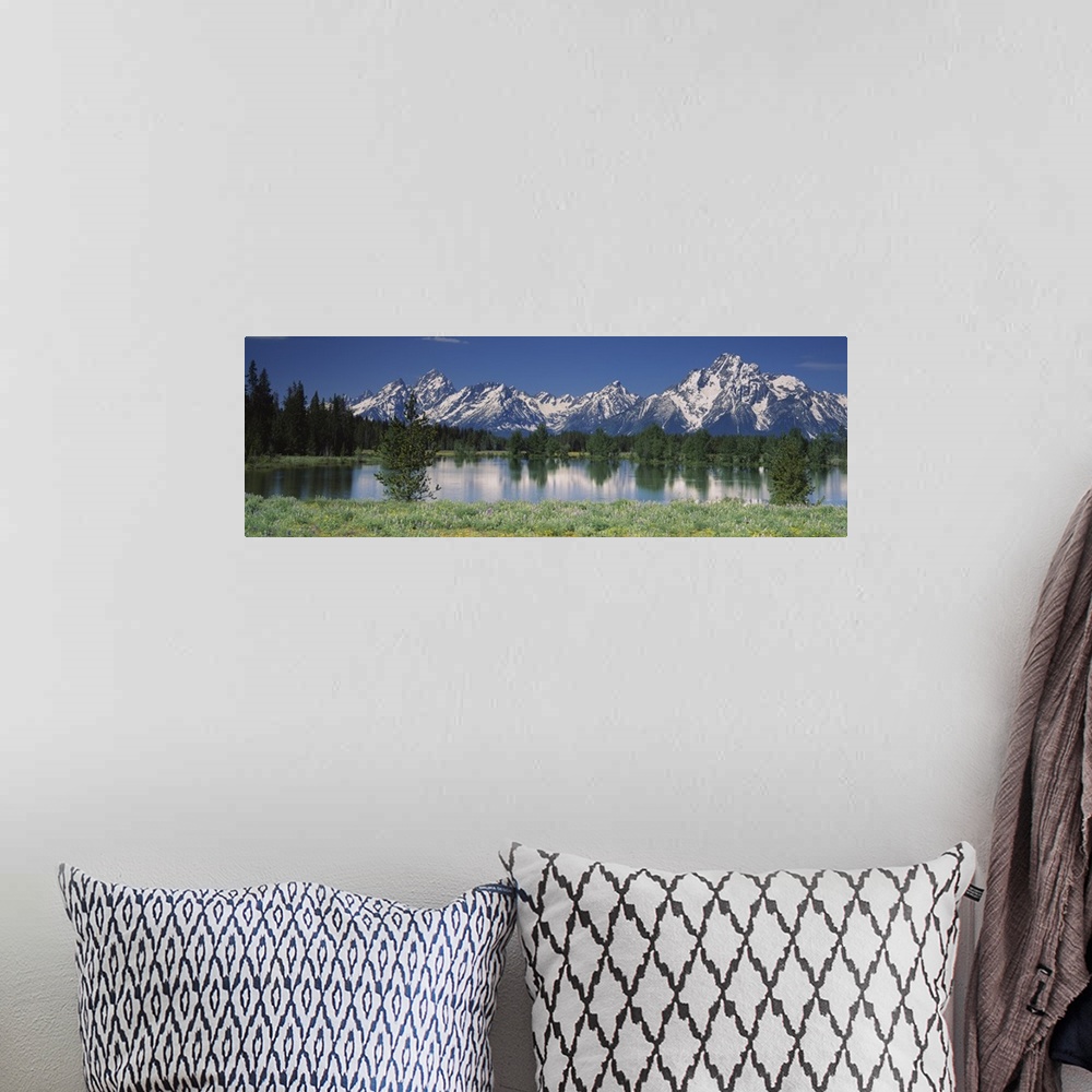 A bohemian room featuring Long canvas of snow capped mountains in the back of a forest reflected onto the waterfront.