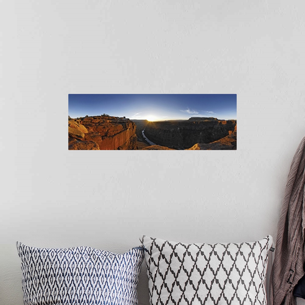 A bohemian room featuring A large panoramic photograph of the Grand Canyon with the river running through it and the sun se...