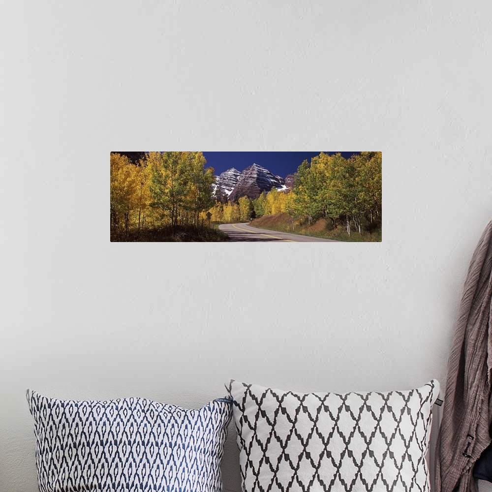 A bohemian room featuring Large, horizontal photograph of a road winding through a fall colored forest, the Maroon Bells in...
