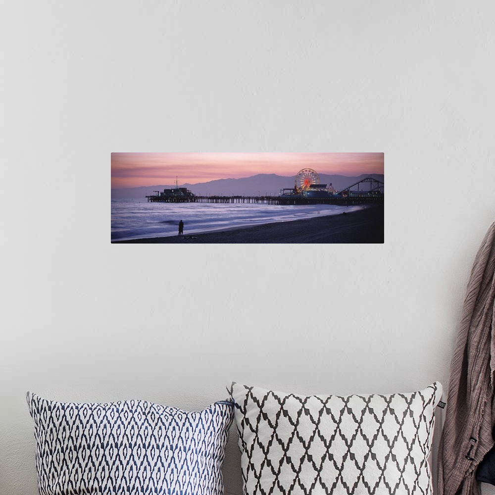 A bohemian room featuring A panoramic shot taken of the Santa Monica pier during sun down with a couple standing on the bea...
