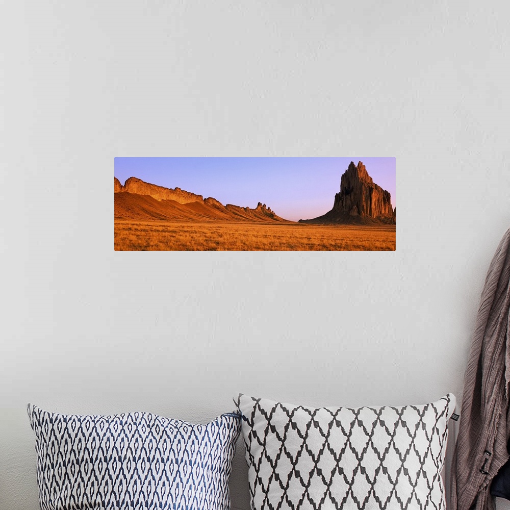 A bohemian room featuring Ship Rock mountain is skewed to the right side of this panoramic piece with vast desert terrain t...