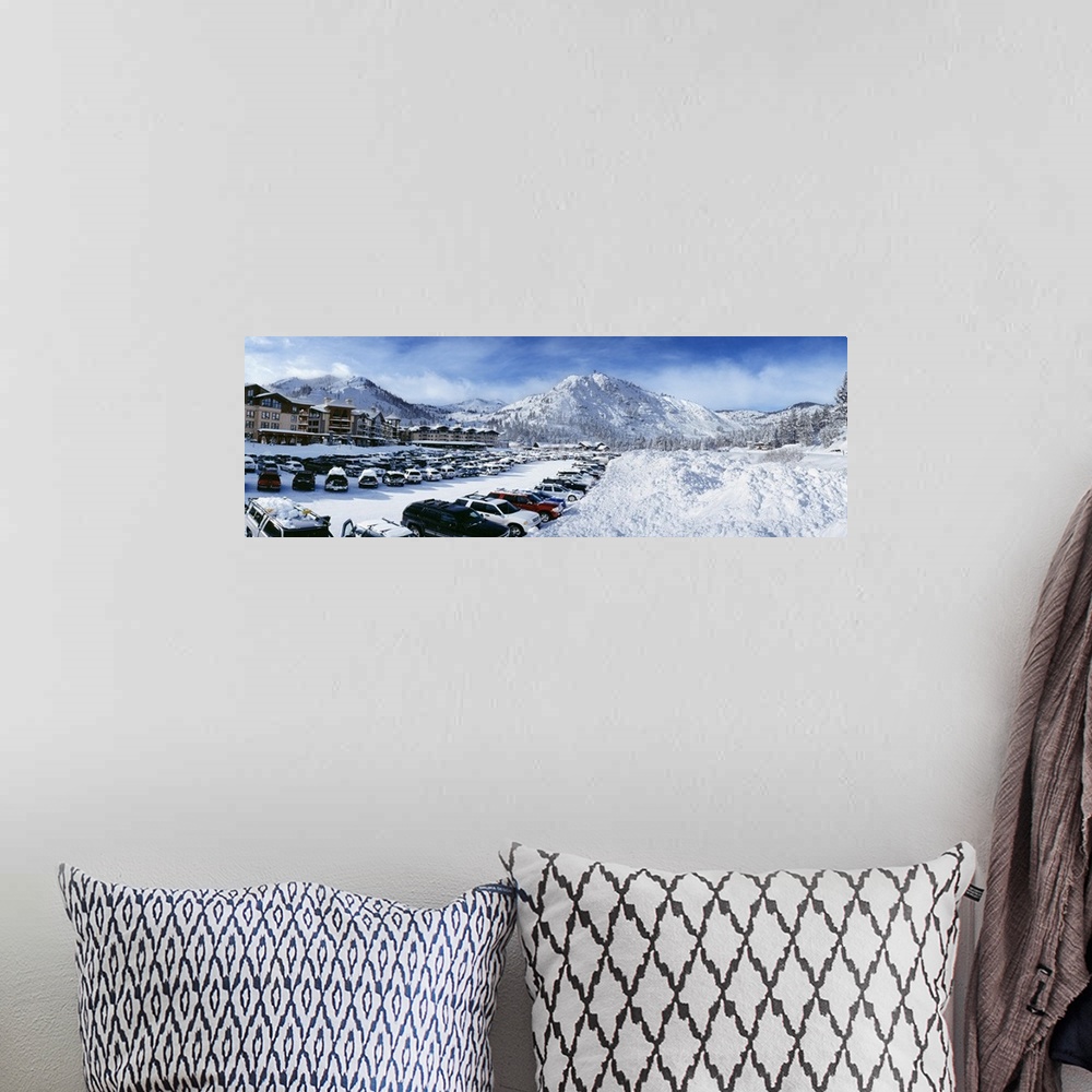 A bohemian room featuring Snow covers the mountains, ground and cars that sit parked at a large ski resort in Lake Tahoe.