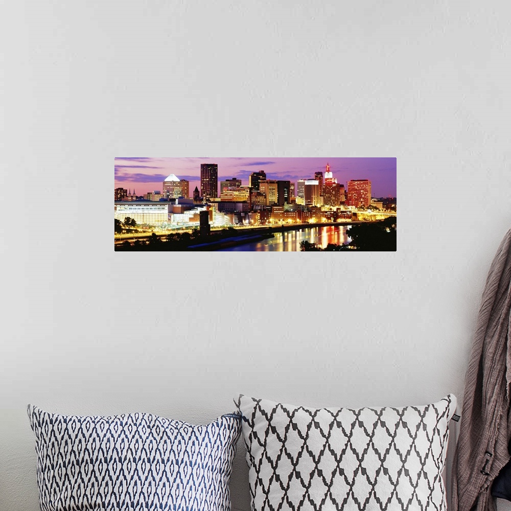 A bohemian room featuring Panoramic photograph of city skyline on a cloudy night.  The building lights are glowing and they...