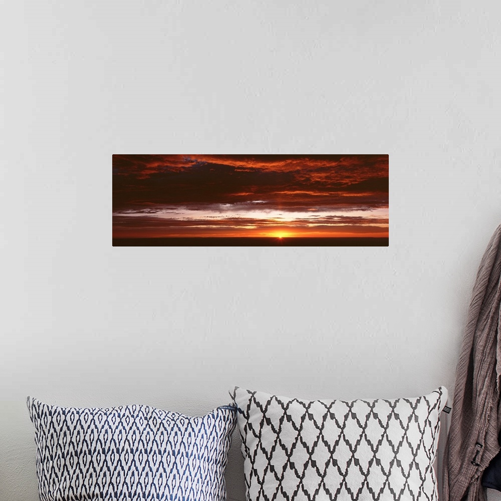 A bohemian room featuring Panoramic photograph of a sunset just hitting the horizon and lighting up a cloud filled sky with...