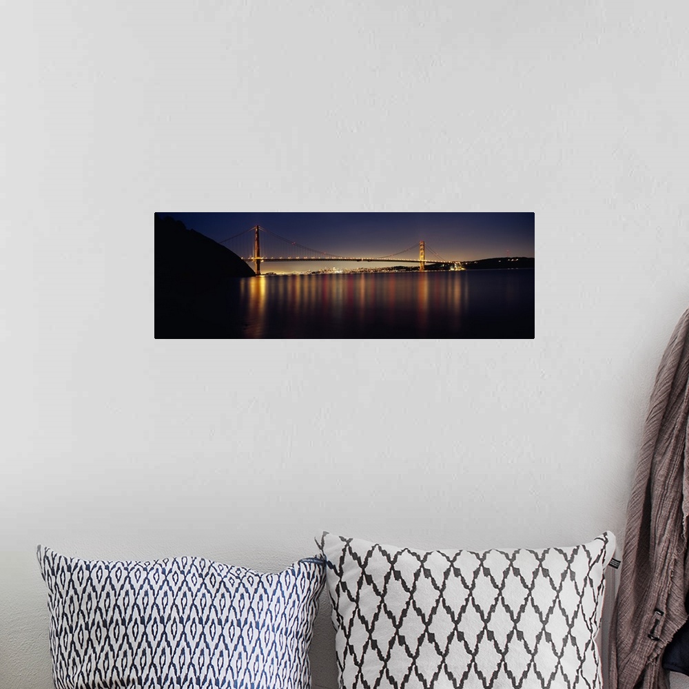 A bohemian room featuring Wide angle photograph of the Golden Gate Bridge in the distance, lit at night and reflecting over...