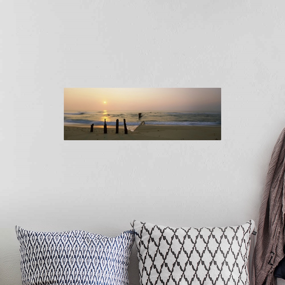 A bohemian room featuring Posts and tide break on the beach at sunrise, Cape Hatteras National Seashore, North Carolina, USA