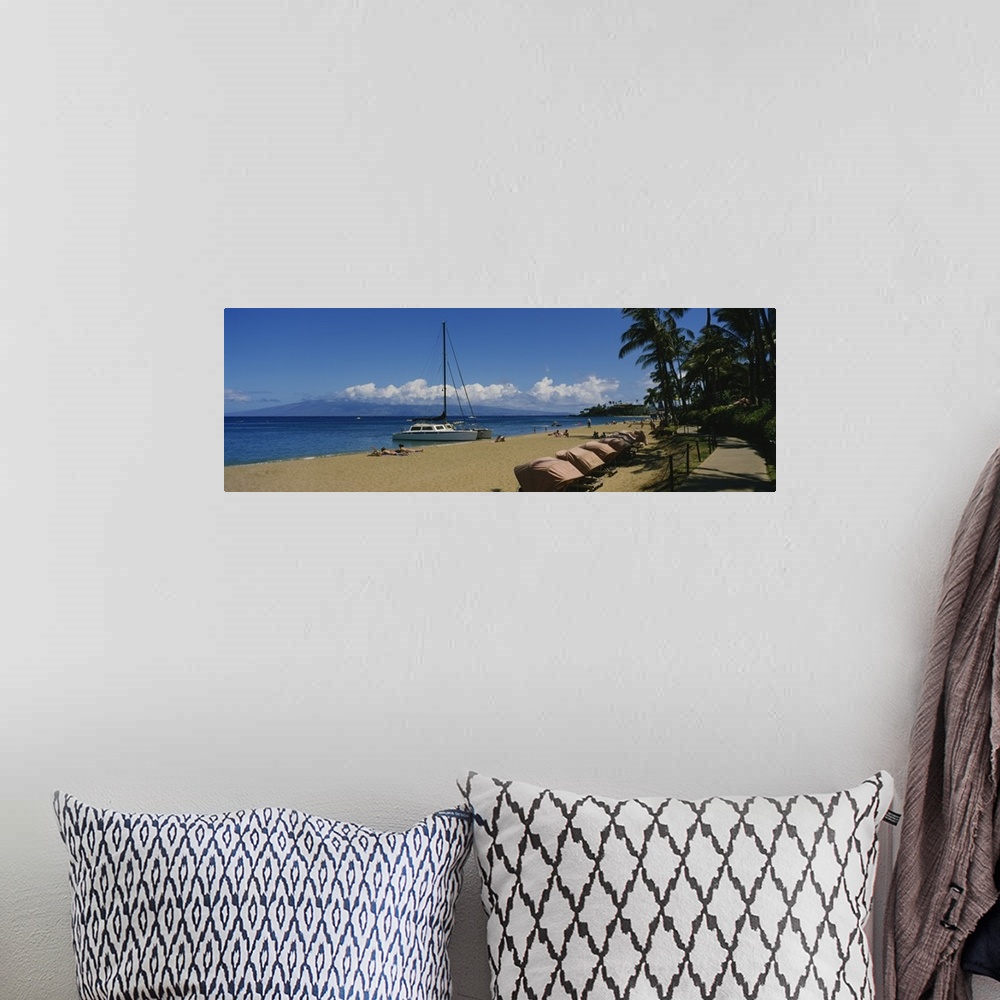 A bohemian room featuring Panoramic photograph of shoreline filled with beachgoers and docked sailboats under a cloudy sky.