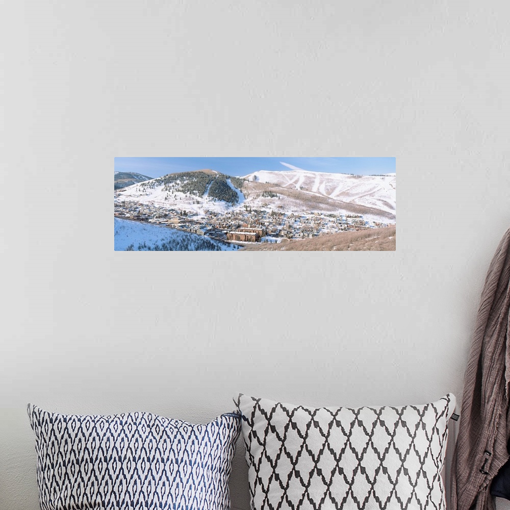 A bohemian room featuring Wide angle photograph on a large canvas of a distant town in a valley, surrounded by a snow cover...
