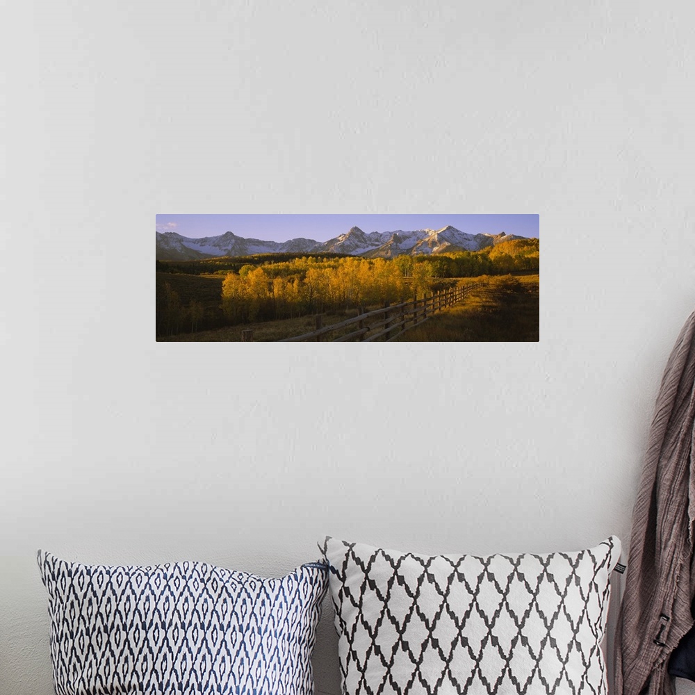 A bohemian room featuring Wide angle photograph on a large canvas of a wooden fence running through a golden fall landscape...