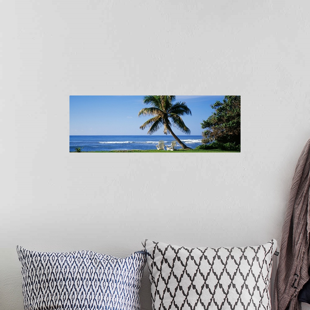 A bohemian room featuring This is a panoramic photograph of a grassy lawn that grows up the shoreline where two lounge chai...