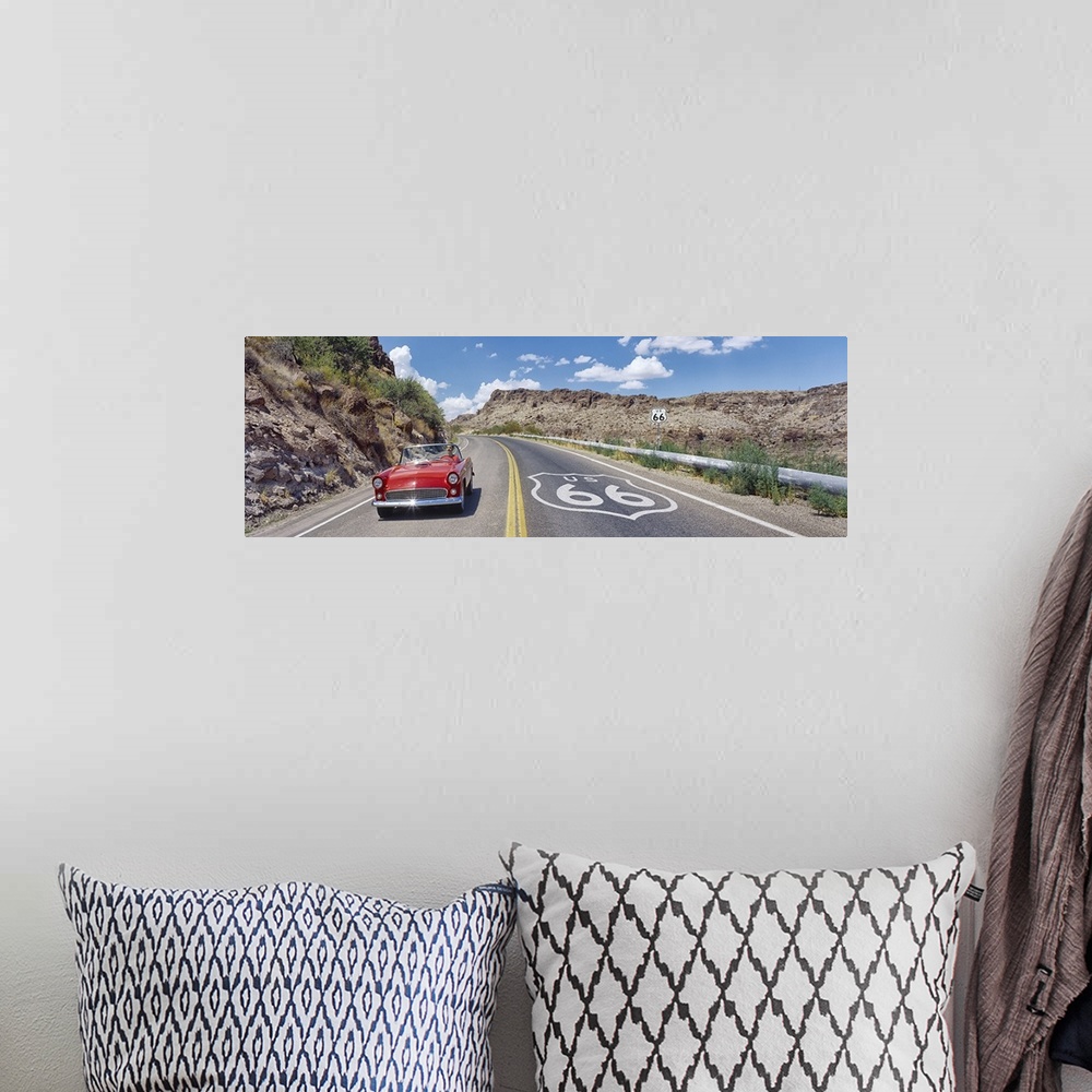 A bohemian room featuring Panoramic photograph of classic car on highway winding through the mountains under a cloudy sky.