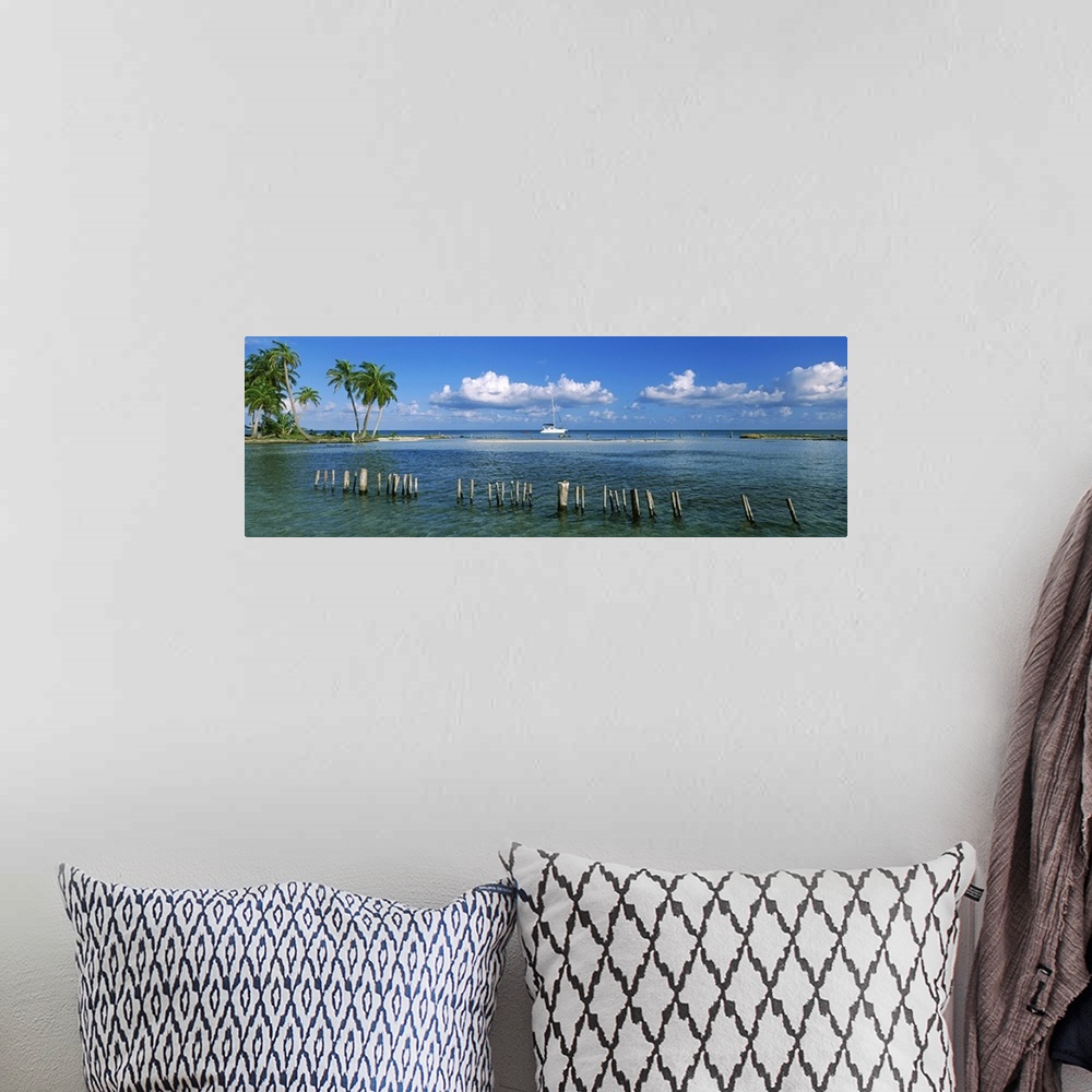 A bohemian room featuring Wooden posts in the sea with a boat in background, Laughing Bird Caye, Victoria Channel, Belize