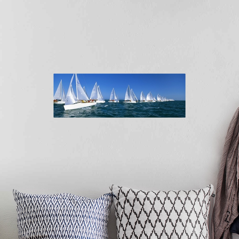 A bohemian room featuring Big, landscape photograph of many white yachts in a line, beneath a blue sky, during a race in th...