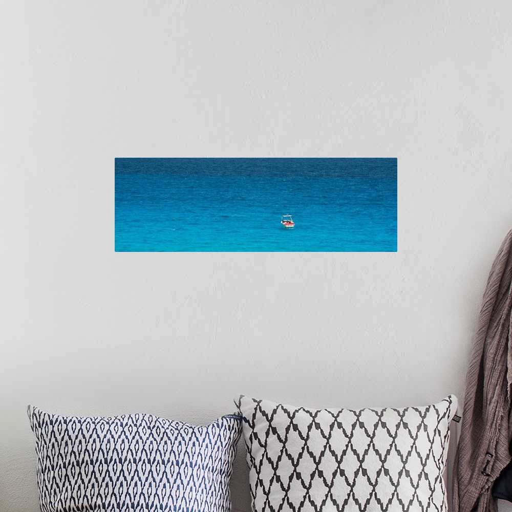 A bohemian room featuring Panoramic photograph of a single boat floating in the bright blue ocean. From the Viva Mexico Pan...