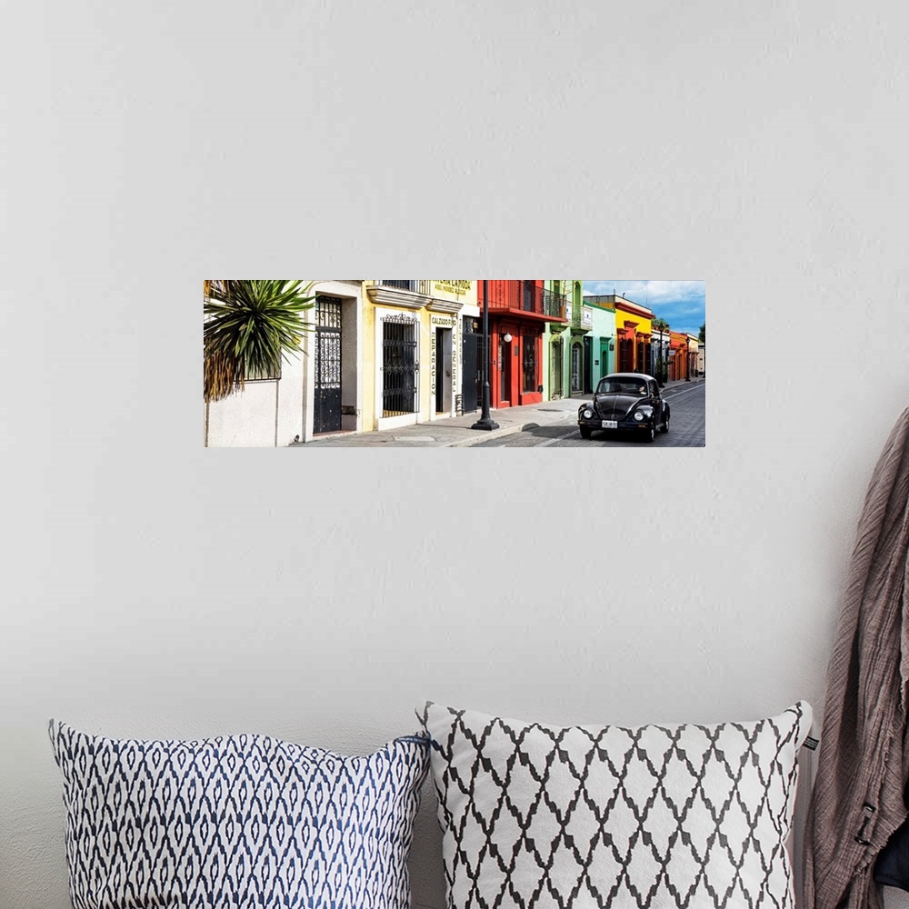 A bohemian room featuring Panoramic photograph of a classic black Volkswagen Beetle driving up a colorful street in Mexico....