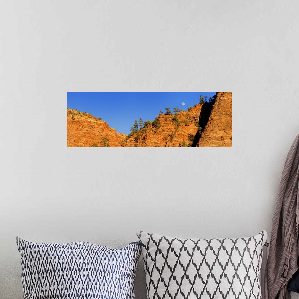 A bohemian room featuring The moon is visible over the edge of the orange cliffs in Zion National Park in Utah.