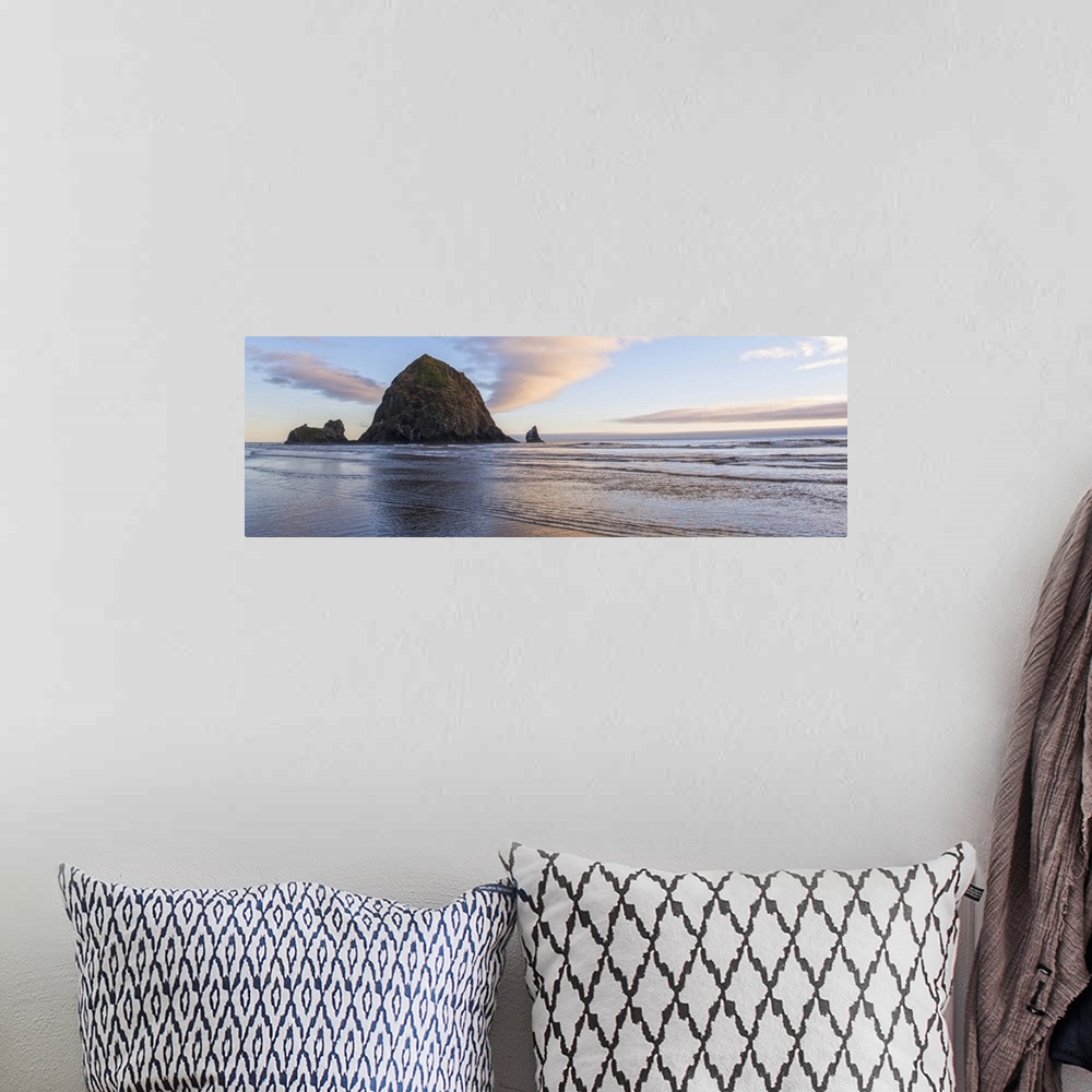 A bohemian room featuring Panoramic photograph of Haystack Rock with a pink and purple sunset and reflections on the water.