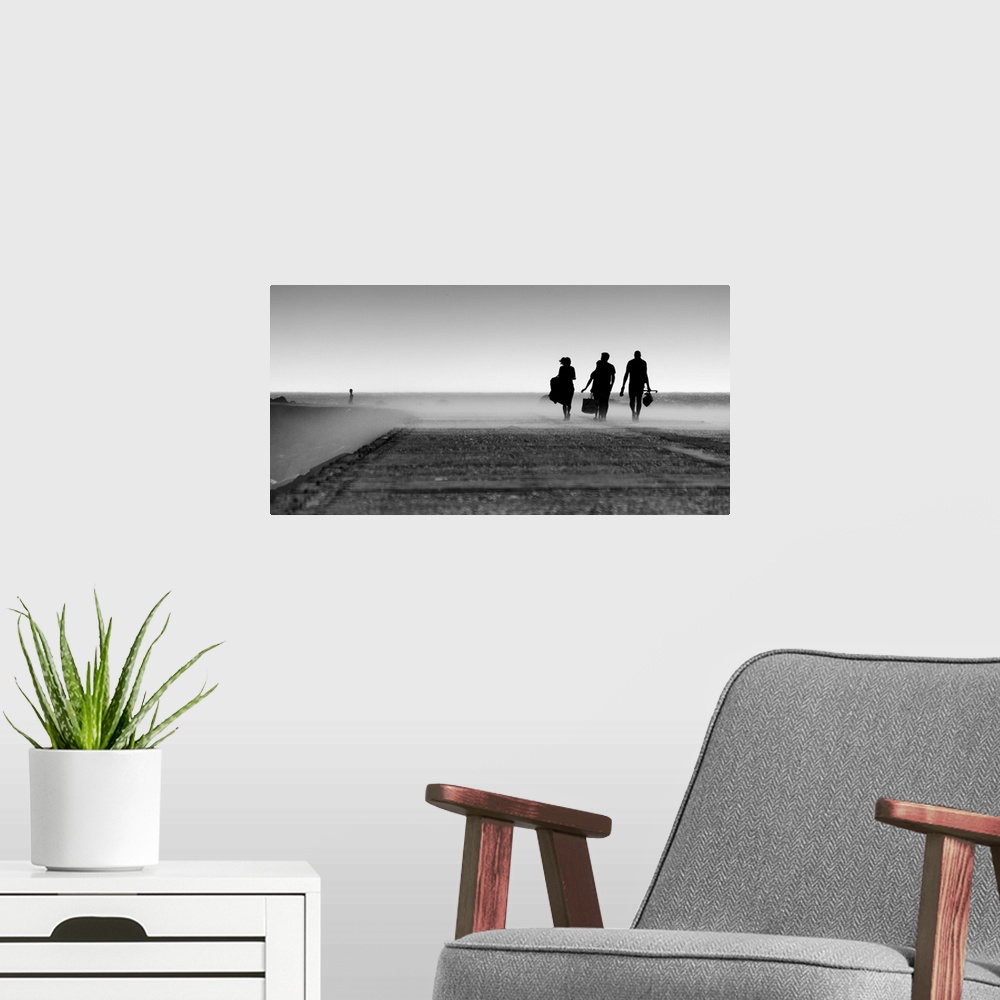 A modern room featuring A black and white photograph of three silhouetted figures walking toward a mist.