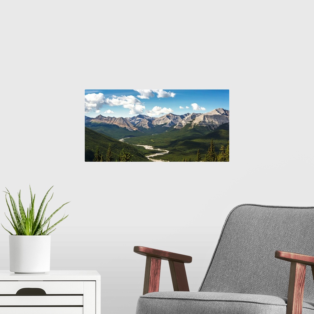A modern room featuring Panorama of river valley and mountain range with blue sky and clouds, Bragg Creek, Alberta, Canada.