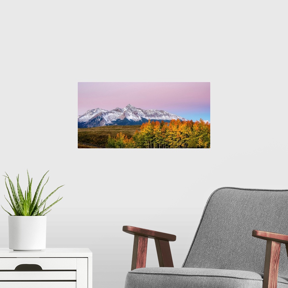 A modern room featuring Landscape photograph of a snowy mountain range with colorful Fall trees in the foreground and a c...