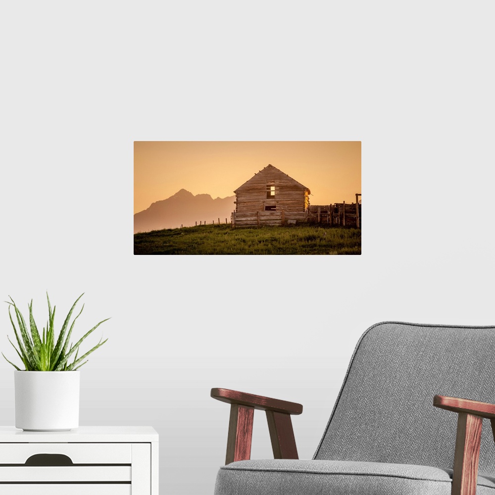 A modern room featuring Warm photograph of an old wooden barn on a hilltop with a silhouette of mountains in the background.