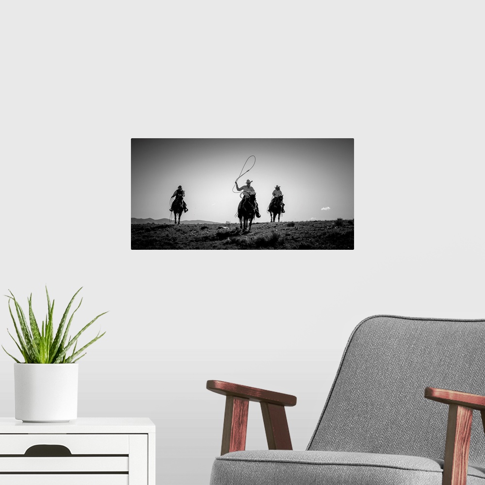 A modern room featuring Black and white photograph of three cow girls on horseback with their lassos out.