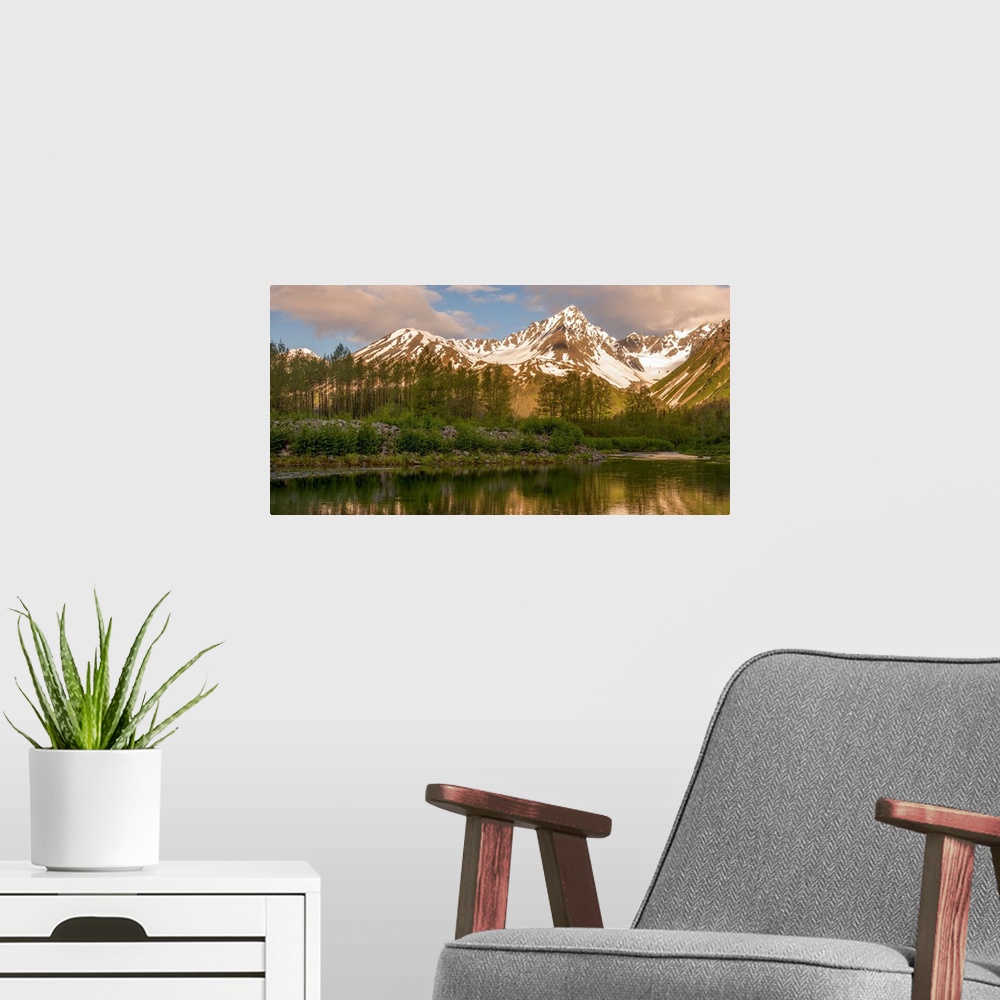 A modern room featuring Landscape photograph of a lake in front of snowy mountain peaks with warm lighting.