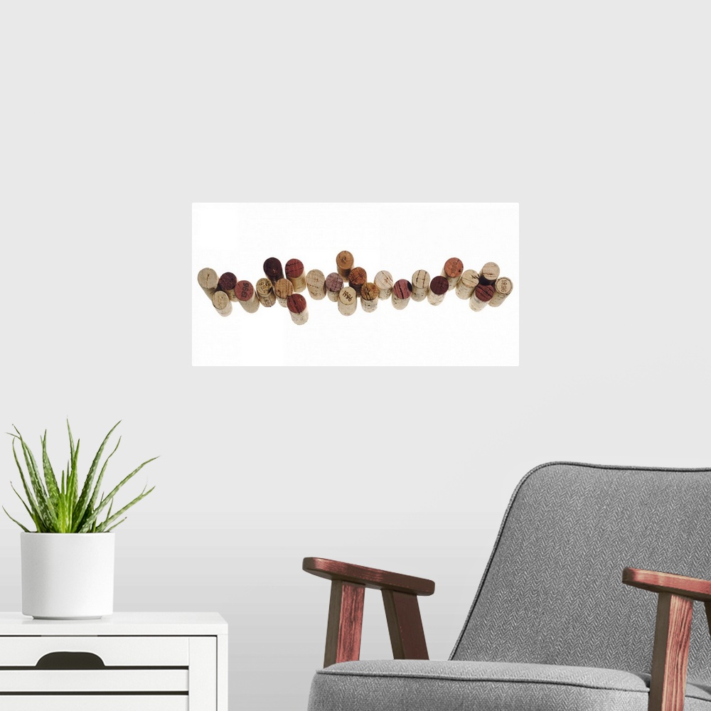 A modern room featuring Corks from various wine bottles stand straight up and are lined next to each other on a white sur...