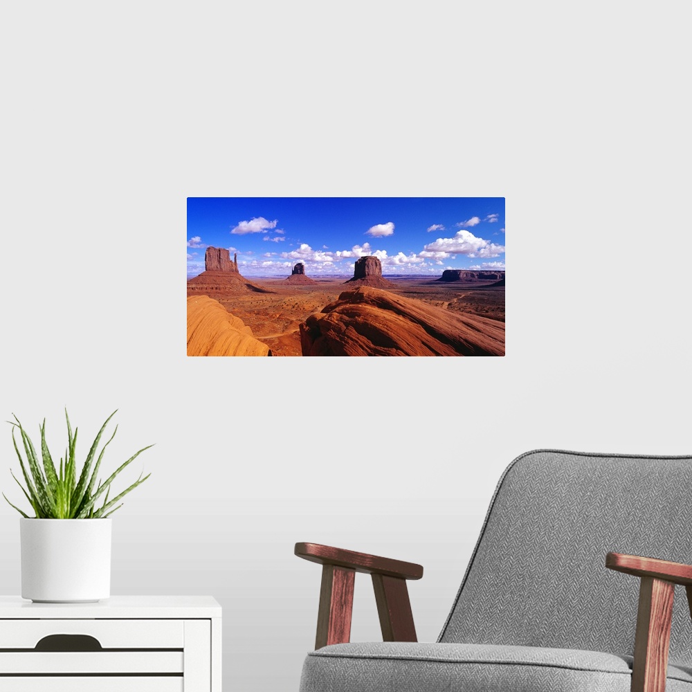 A modern room featuring Large panoramic photograph taken of Monument Valley with giant rock formations seen in the distan...