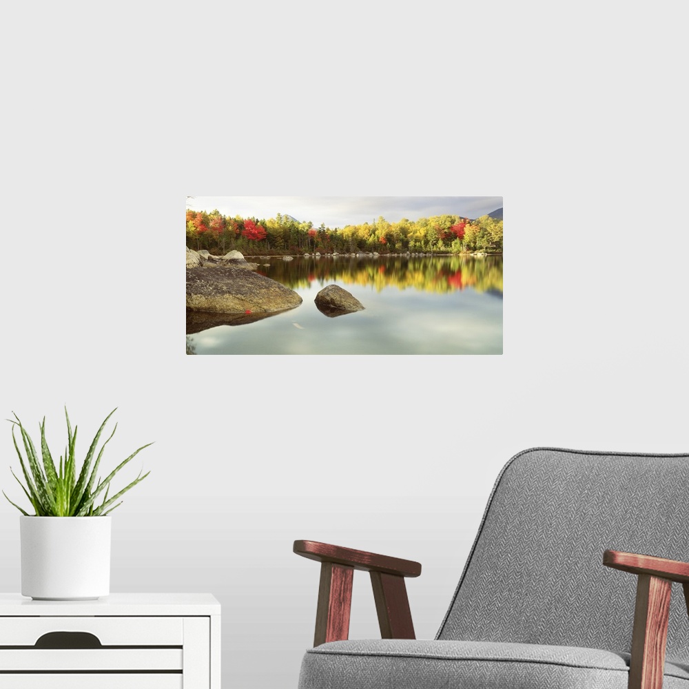 A modern room featuring Landscape photograph of a calm body of water with large rocks breaking through the surface around...